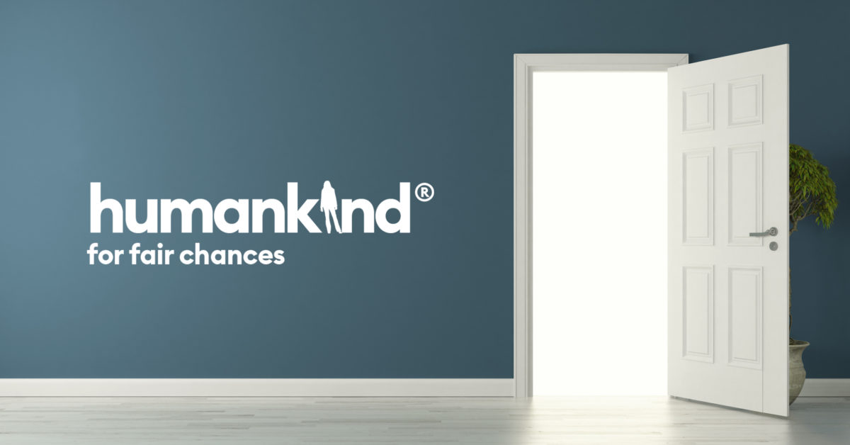 A blue wall with the words "Humankind- for fair chances" written on it, and an opened door
